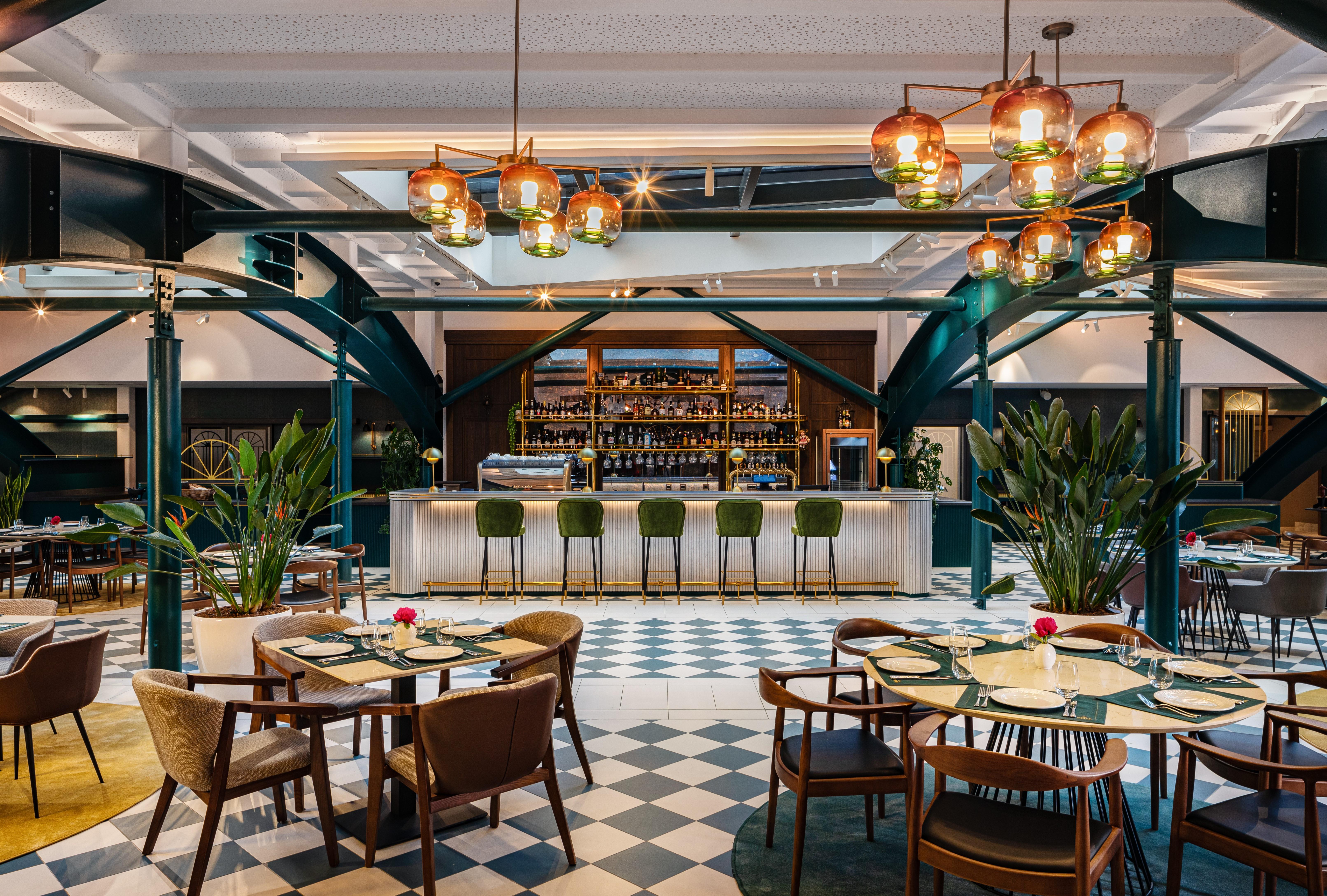 Grand Hotel Millennium Sofia Bagian luar foto The photo showcases a stylish restaurant interior. There are several tables set with chairs arranged around them, featuring a mix of styles. In the background, a sleek bar counter is visible, stocked with various bottles. The bar is complemented by e